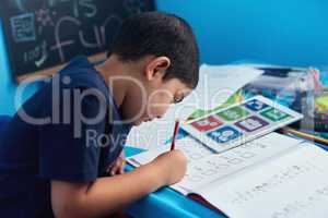 Another day to learn, another day to grow. an adorable little boy completing a school assignment at his desk.