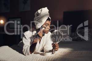 Pamper time is the closest experience to heaven on earth. a young woman giving herself a facial at home.
