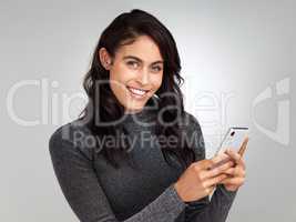 I think I have a crush. a young woman using her cellphone while standing against a grey background.