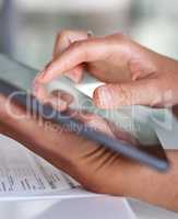 Navigating plenty of helpful business info online. Closeup shot of an unrecognisable businesswoman using a digital tablet while going through paperwork in an office.