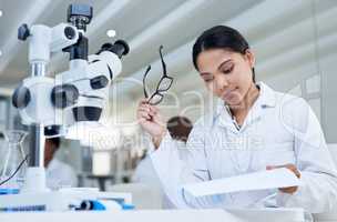 Conducting some lab-based research. a young scientist going through paperwork in a lab.