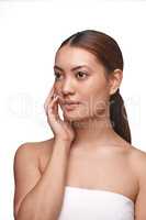 Learn to love your natural skin tone and complexion. a beautiful young woman touching her face while standing against a white background.