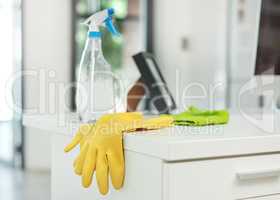 A clean office is a safe office. a pair of rubber gloves and disinfectant spray on a desk in a modern office.
