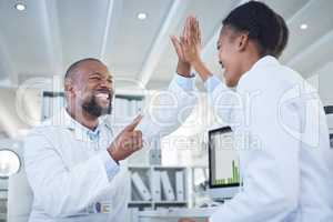 Science saves the day. two scientists giving each other a high five while conducting research in a laboratory.