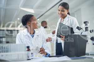 Inspired minds inspire each other. two young scientists having a discussion in a laboratory.