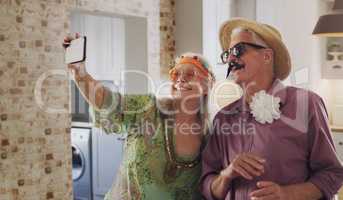 Say cheese. a happy senior couple standing together in costume and using a cellphone to take selfies.