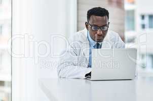 Doctors tools get more advanced by the day. a young doctor using a laptop at his desk.