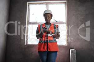 Building connections one brick at a time. a young woman using a smartphone while working at a construction site.