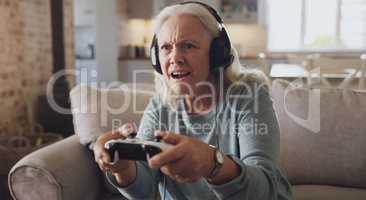 What I died. a senior woman sitting alone on the sofa at home and wearing headsets while gaming.