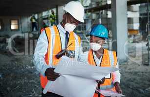 Promoting teamwork promotes productivity. a young man and woman going over building plans at a construction site.