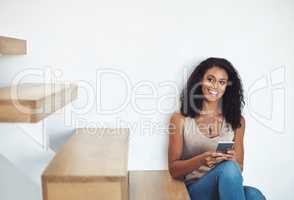 Relaxed woman texting on phone while thinking, planning and dreaming of interior design ideas for new property. Smiling, happy and cheerful homeowner searching or browsing decorations for real estate