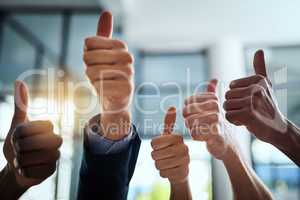 Thumbs up, support and hand sign shown by professional corporate business people in an office together. Employees and colleagues working and showing unity, satisfaction and agreement with thumb sign