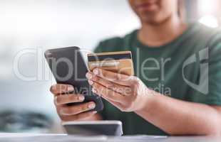 Paying bills minus the bank queues. an unrecognisable woman using a smartphone and credit card at her desk.