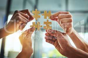 Group of business people holding puzzle pieces. Professionals connect and collaborate together inside office building. Closeup of hands, and team working together on a new strategy for success
