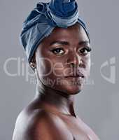Showing off nothing but her beautiful face. a beautiful young woman wearing a denim head wrap while posing against a grey background.