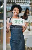 Opening shop for the day. Portrait of a young woman holding an open sign in a cafe.