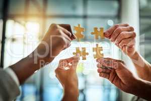 Group of business people holding puzzle pieces. Professionals connect and collaborate together inside office building. Closeup of hands, and team working together on a new strategy for success.
