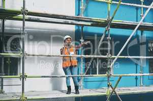 Shes not afraid to delegate and command. a young woman talking on a cellphone while working at a construction site.