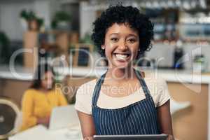 Technology helps business owners remain organised. Portrait of a young woman using a digital tablet while working in a cafe.