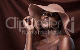 I love the woman Im becoming. a beautiful young woman wearing a hat while posing against a brown background.