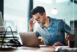 Businessman suffering from a headache or migraine due to stress caused by work deadlines. Professional holding head in pain feeling anxious, overwhelmed and stressed while busy on his computer desk