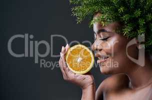 Oranges provide a range of benefits for your skin. a beautiful woman holding an orange and wearing a leaf wreath on her head.