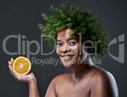 Shes been crowned for her natural beauty. a beautiful woman holding an orange and wearing a leaf wreath on her head.