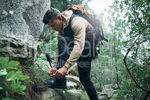 Hike more, worry less. a young man tying his laces while out on a hike.