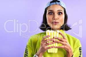 The best movies make you forget about your snacks. Studio shot of a beautiful young woman eating popcorn against a purple background.