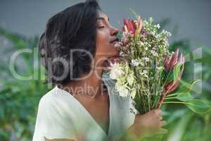Smelling their fragrance has the power to stop time. a beautiful young woman smelling a bouquet of flowers.