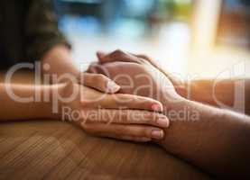 Romantic, caring and in love couple holding hands, wife expressing sympathy and showing support. Female apologizing, comforting or calming upset male on the table at home.