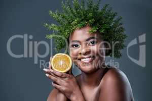 Achieve envy-worthy skin with a envy-worthy beauty regime. a beautiful woman holding an orange and wearing a leaf wreath on her head.