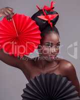 Makeup is not a mask - its art, passion and expression. Studio portrait of a beautiful young woman wearing Asian inspired makeup and posing with origami against a grey background.