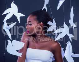 There is a goddess within each of us. Studio shot of a beautiful young woman posing with paper birds against a black background.