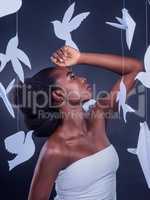 You were born to soar through life with confidence and magnificence. Studio shot of a beautiful young woman posing with paper birds against a black background.