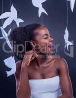 Express your natural beauty freely. Studio shot of a beautiful young woman posing with paper birds against a black background.