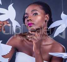Beauty begins the moment you decide to spread your wings. Studio portrait of a beautiful young woman posing with paper birds against a black background.