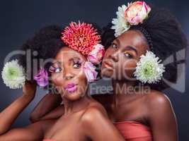 Looking gorgeous while in full bloom. two beautiful women posing together with flowers in their hair.