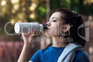 Staying hydrated. an attractive young female athlete drinking water while standing on the basketball court.