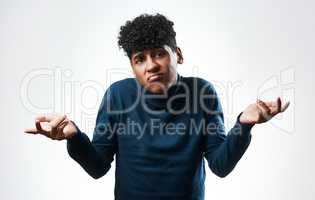 If youre looking for answers, I dont have any. Studio shot of a young man shrugging his shoulders against a grey background.