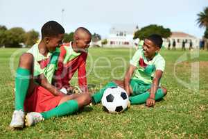 Its always tons of fun on the field. a group of young boys taking a break while playing soccer on a sports field.
