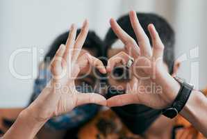 Through sickness and health. a masked young couple making a heart shaped gesture with their hands at home.