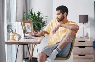 It takes a lot of focus to work from home. a young man using a laptop while working from home.