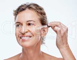 I can see my skin becoming firmer and smoother. a mature woman posing with a serum dropper against her face.