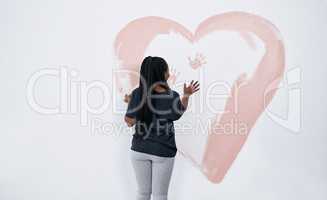 Instead of a Valentines Day card, how about a mural. a young woman painting a heart on a wall.
