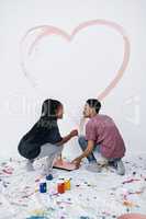Art is love and love is art. a young couple painting a heart on a wall.