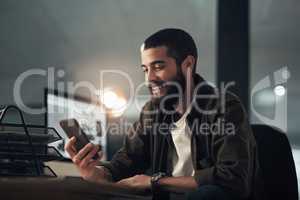 When you want success youll do whatever it takes. a young businessman using a smartphone during a late night at work.