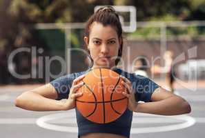 Gaining the skills to win takes time and patience. Portrait of a sporty young woman holding a basketball on a sports court.