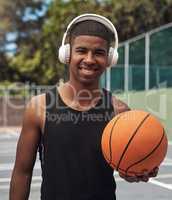 Play with all your heart. Portrait of a sporty young man listening to music while playing basketball on a sports court.