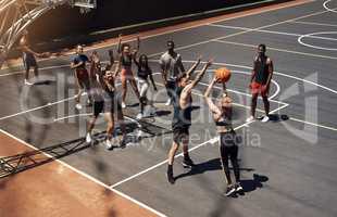 Everyone is totally immersed in the game. a group of sporty young people playing basketball on a sports court.